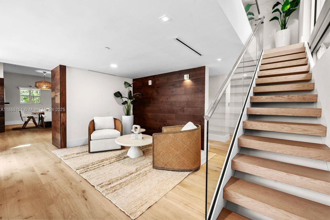 Elegant living room with wide-plank wood floors, open staircase, and natural light — modern coastal design in the heart of South Beach.