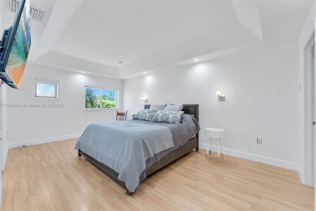 Cozy bedroom with wood-look floors, natural lighting, and neutral décor—perfect for comfort and relaxation.