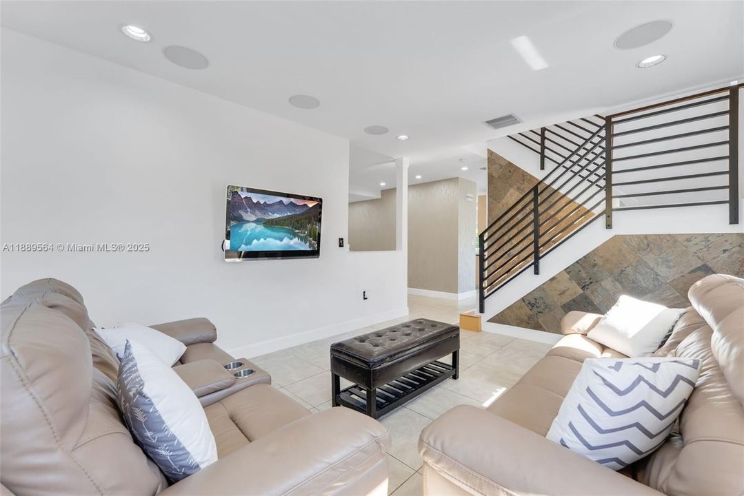 Bright open-concept living room with modern finishes, recessed lighting, and large impact windows offering abundant natural light.
