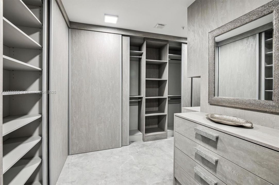 - Primary Spacious L-Shaped Walk-In Closet Custom Built Out Wooden Cabinetry and Shelving with Michael Aram Hardware and Accessories.