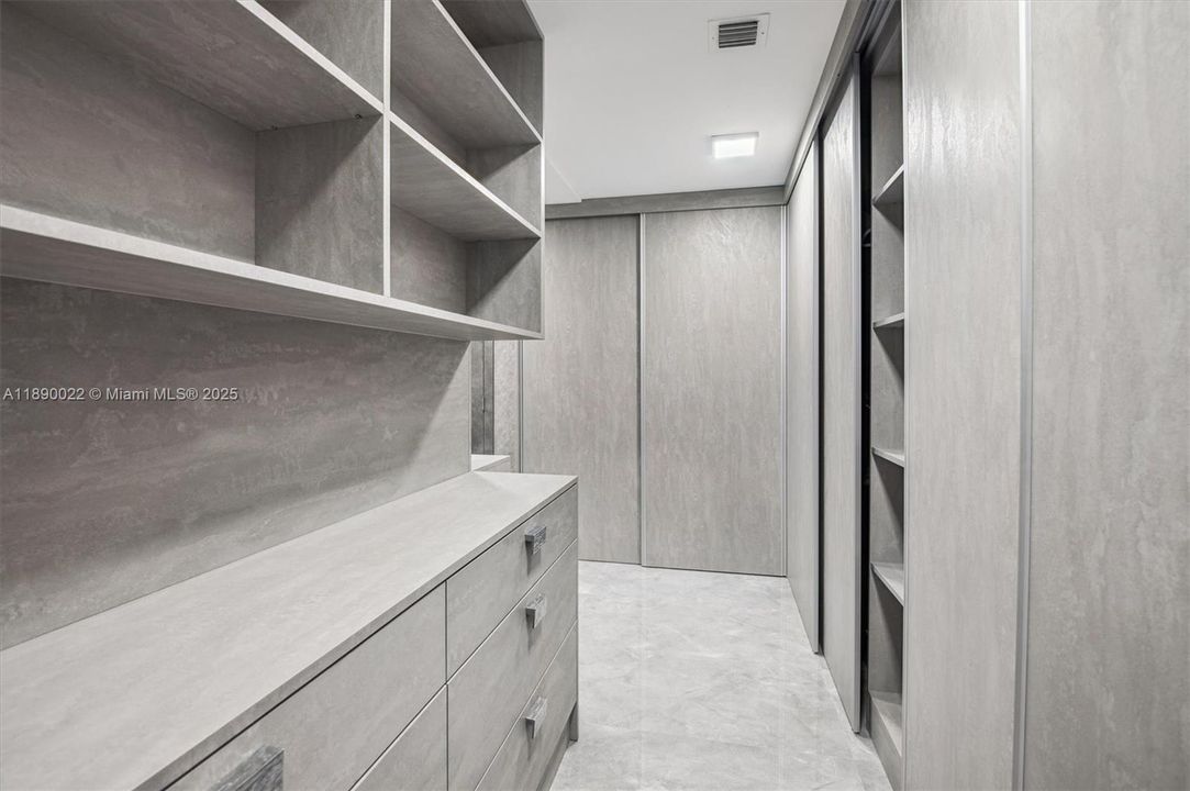 Spacious L-Shaped Primary Walk-In Closet w/ Ample Display Shelving & Drawer Space.