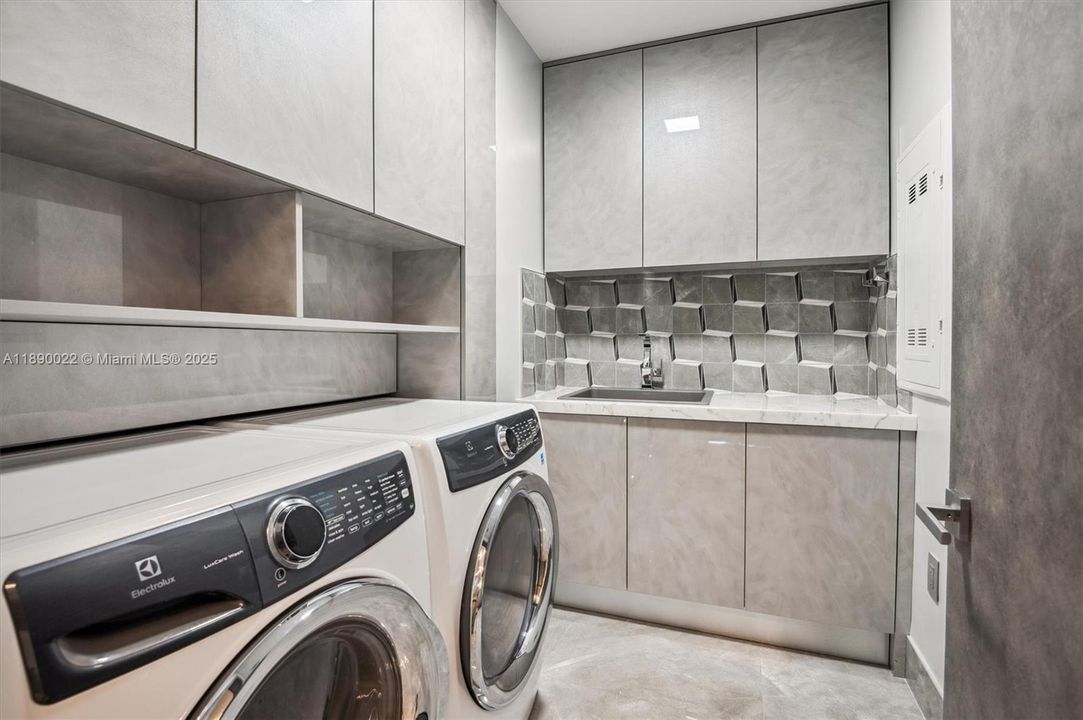 Laundry Room w/ Ample Storage added w/ Custom Cabinetry, 3D Porcelain Backsplash and Blanco Laundry Sink. Electrolux Luxcare Front Load Washer and Dryer.