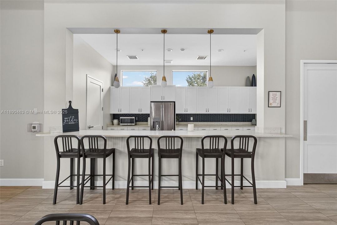 The community clubhouse features a sleek catering kitchen with oversized island seating — perfect for parties, game nights, or hosting family without having to squeeze everyone into your own living room.