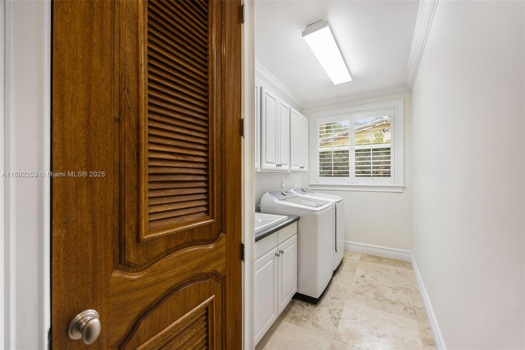 Laundry room with built-in cabinetry and connecting to double car garage