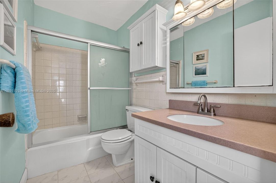 Ensuite primary bathroom with updated flooring, vanity, storage cabinet, mirror & lighting
