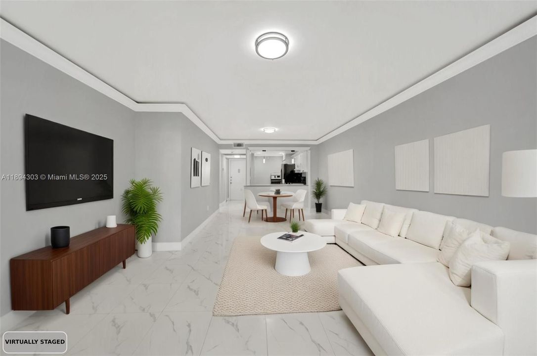 This bright, open living/dining space shows off the full renovation — glossy new marble-look tile floors throughout, fresh light gray paint on the walls, crisp new crown molding and baseboards, and updated modern lighting.