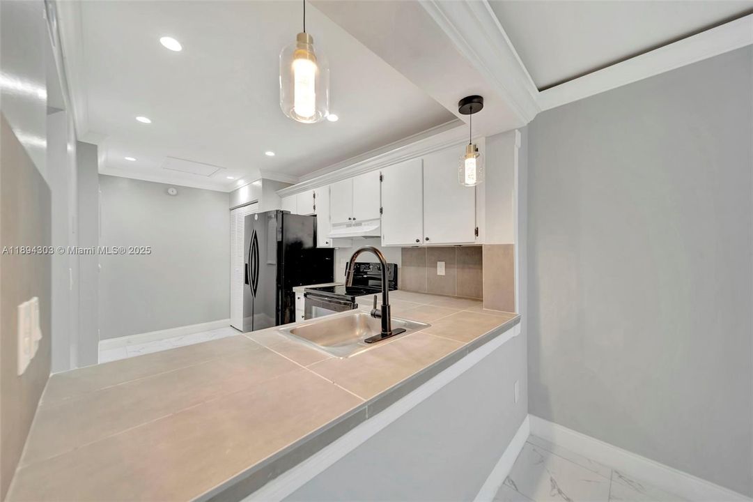 Sleek pass-through bar, statement pendant lights, and a deep sink with matte black fixture — perfect for serving, hosting, and hanging out.