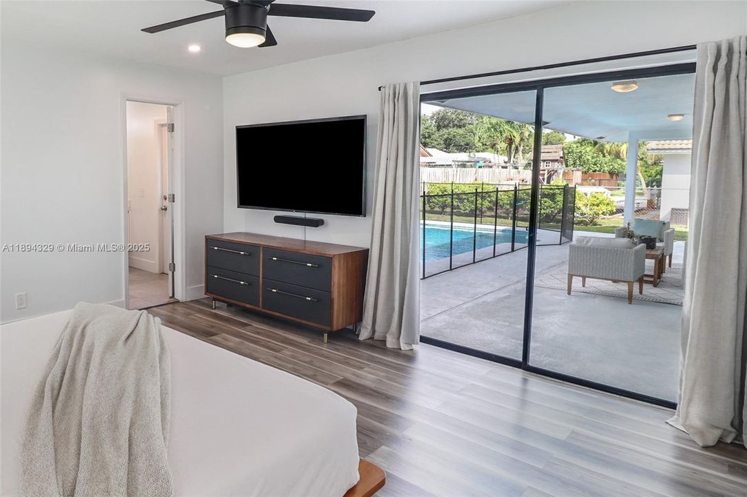 A large sliding glass door opens to a tranquil view of the pool and surrounding patio, allowing natural light to pour in and offering a peaceful connection to the outdoors.