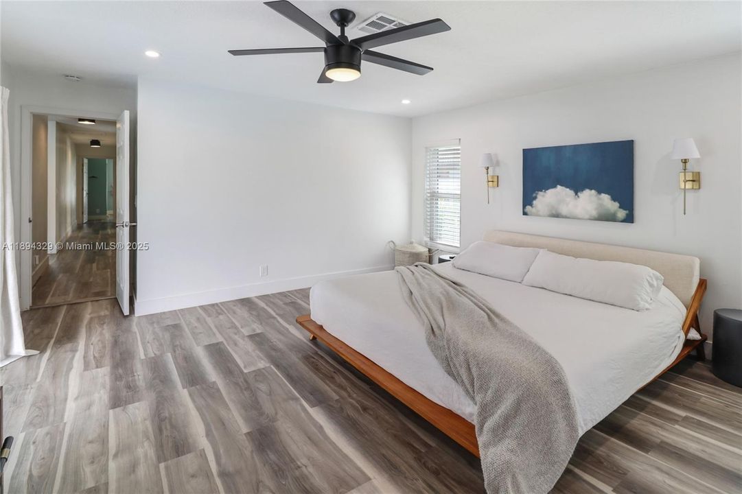 As you exit the private en-suite bathroom of the spacious primary bedroom, your gaze extends down a welcoming corridor. This hallway leads to three additional bedrooms and a second full bathroom, offering a thoughtful separation between shared and private living spaces. The layout ensures comfort and privacy for every member of the household.