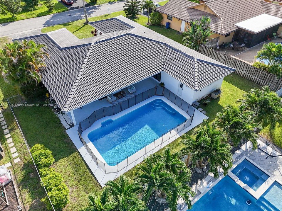 This inviting pool area is complemented by a newly installed tile roof, added in January 2024, featuring a modern color that beautifully contrasts with the vibrant blue of the water. The pool itself was resurfaced in 2023 and upgraded with a saltwater system, replacing the previous chlorine setup—offering a more gentle and low-maintenance swimming experience. The surrounding landscape is well-kept, enhancing the overall appeal of this outdoor retreat.