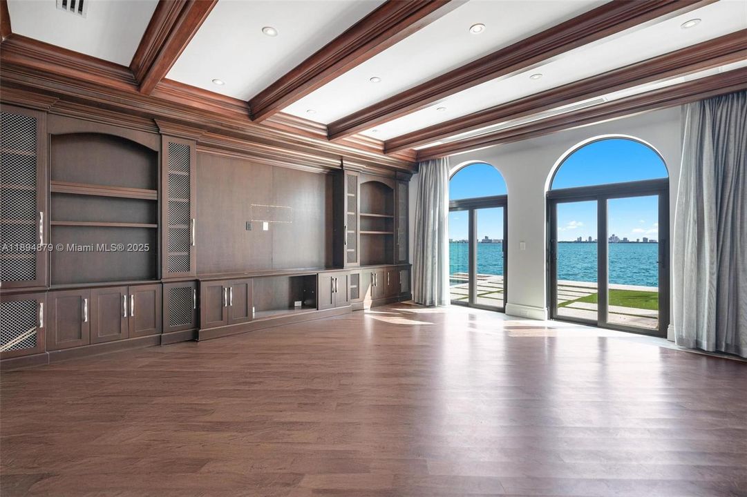 Waterfront media lounge with full-wall cabinetry and sweeping bay/skyline views