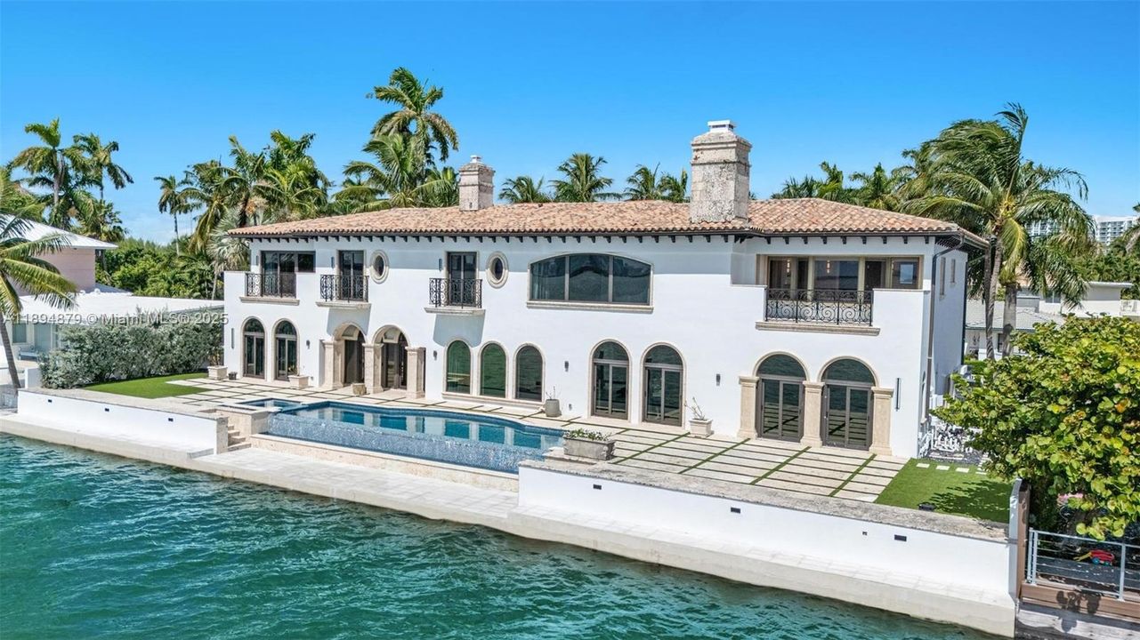 Mediterranean-style bayfront façade with arches, iron balconies & infinity pool