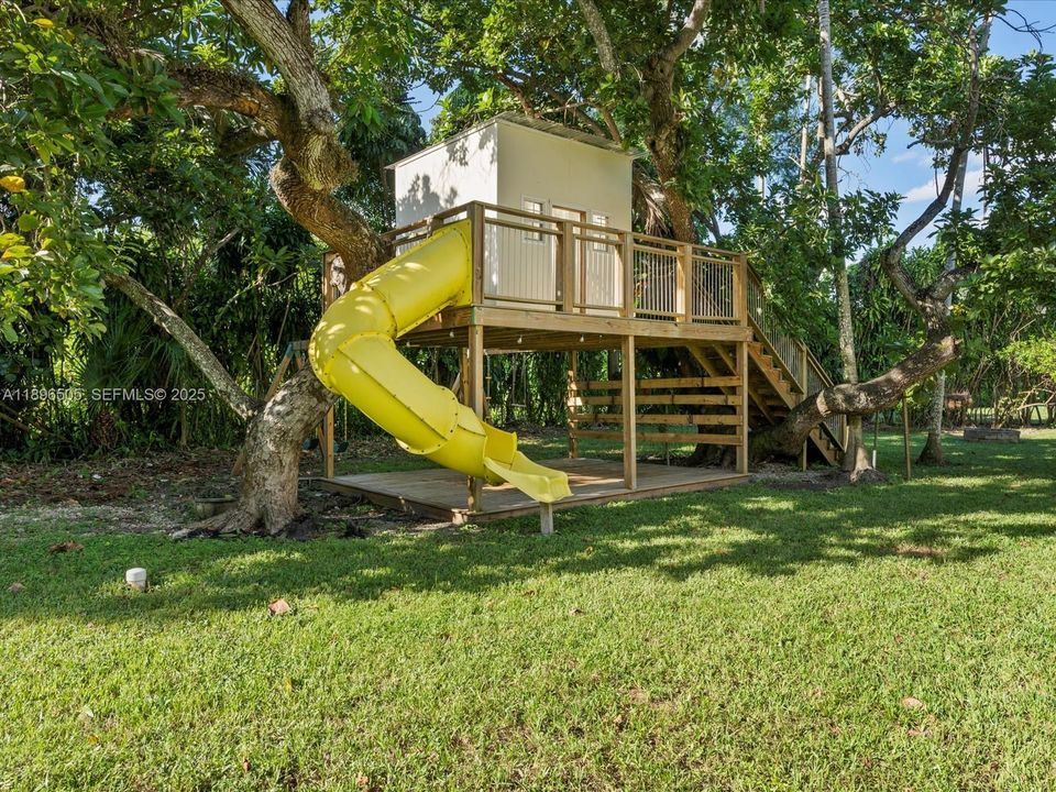 One-acre fenced yard with treehouse, jungle gym, covered outdoor kitchen, and deck — perfect for kids, pets, and entertaining, with space to add a tennis or pickleball court.