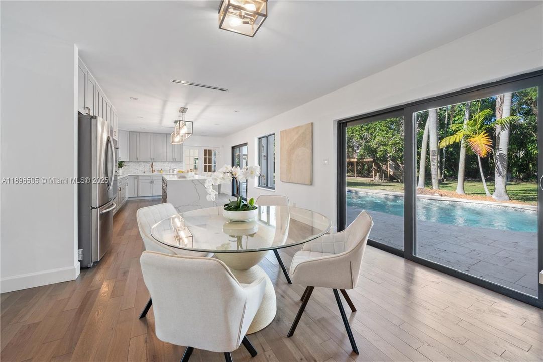 Gourmet kitchen with a large island, custom cabinetry, and stainless steel appliances overlooking the sparkling pool and lush backyard