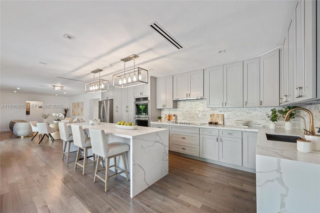 Gourmet kitchen with a large island, custom cabinetry, and stainless steel appliances overlooking the sparkling pool and lush backyard