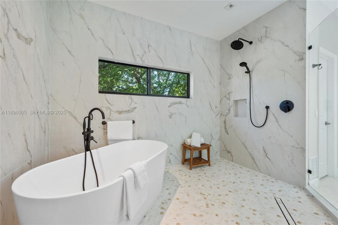 Spa-style primary bath with oversized shower boasting four shower heads, plus a soaking tub with window views — the perfect blend of luxury and relaxation.