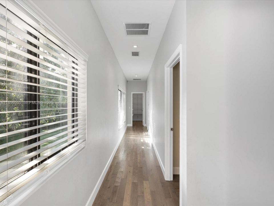 Primary suite privately situated at the opposite end of the home, with additional closet space conveniently located at the end of the hallway.