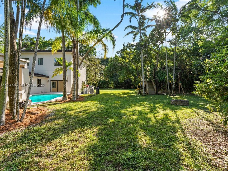 One-acre fenced yard with treehouse, jungle gym, covered outdoor kitchen, and deck — perfect for kids, pets, and entertaining, with space to add a tennis or pickleball court.