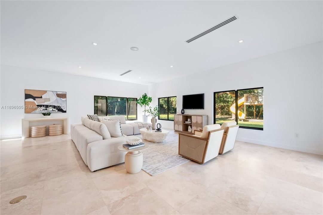 32’x27’8” great room surrounded by windows and a wet bar — a spacious, light-filled layout that allows multiple vignettes for living, dining, family, and seating areas.