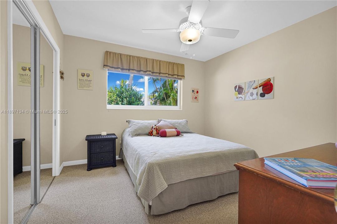 Comfortable guest bedroom with ceiling fan and neutral tones.
