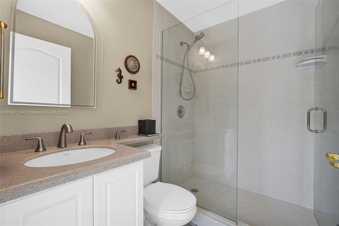 Bath with sink, glass shower, and designer tile details.