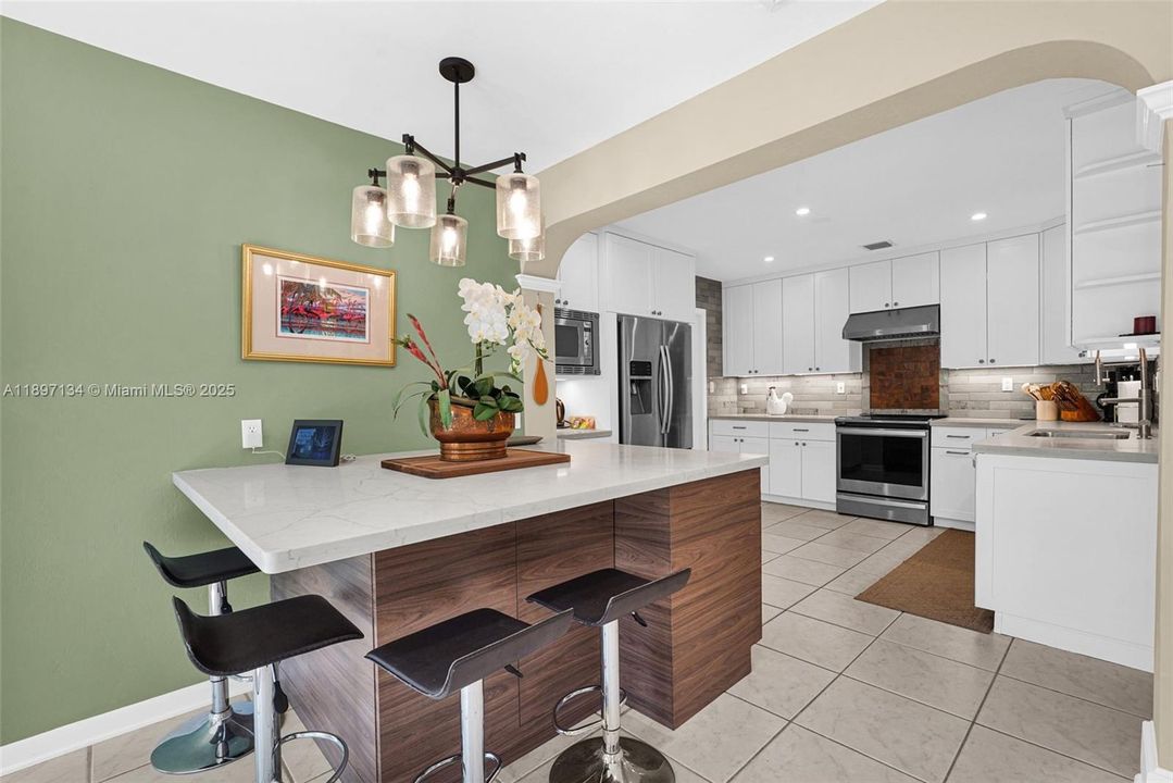 Remodeled kitchen featuring stainless steel appliances, custom cabinetry, and eat-in bar.