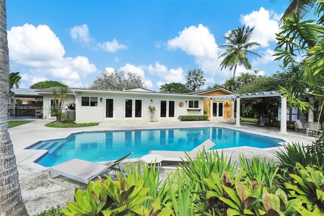 Resort-style pool surrounded by tropical landscaping in private backyard oasis.