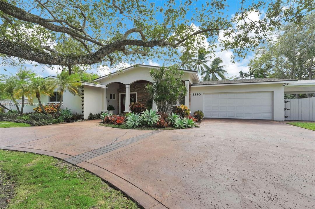 Front exterior showcasing circular driveway, manicured landscaping, and 2-car garage.
