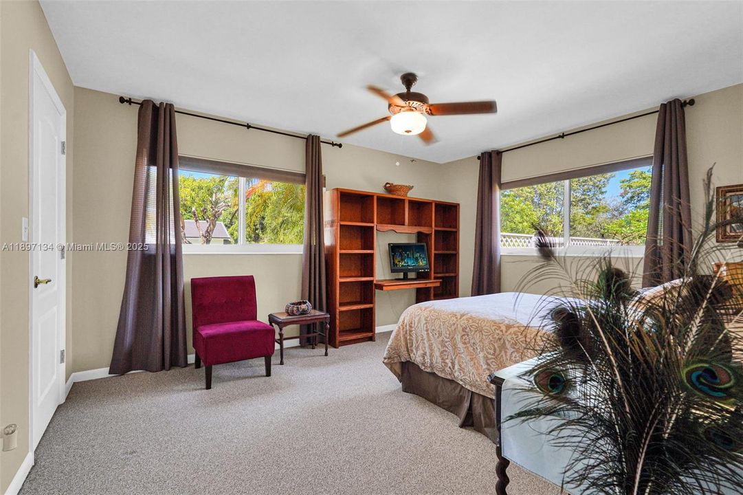 Spacious bedroom with large windows and backyard views.
