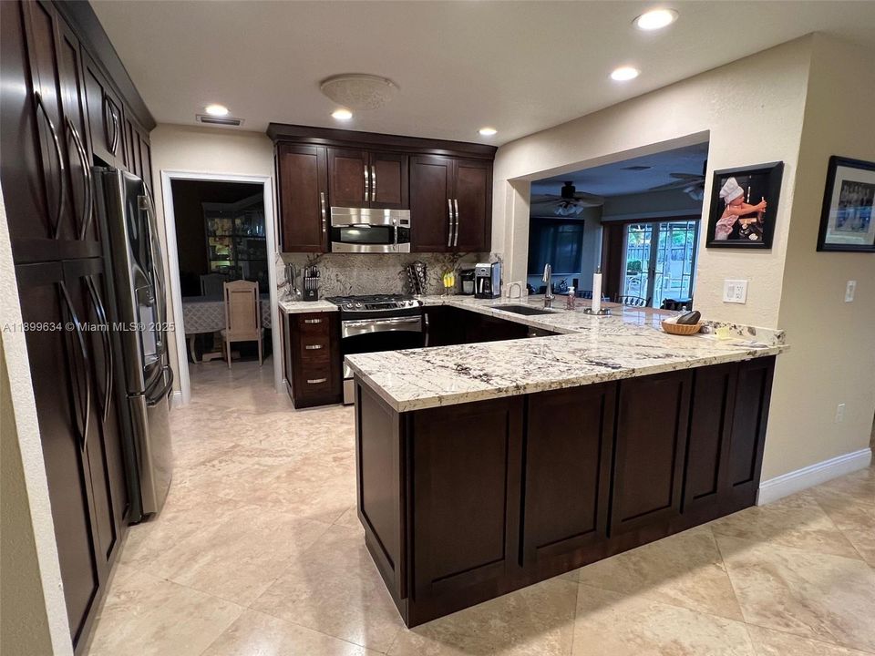 Custom wood cabinets with soft-closing doors and pull out drawers for pantry, stainless steel appliances, gas stove/oven and granite countertops