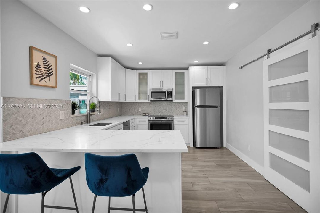 Crisp white cabinetry and designer lighting enhance this kitchen’s clean, timeless look.