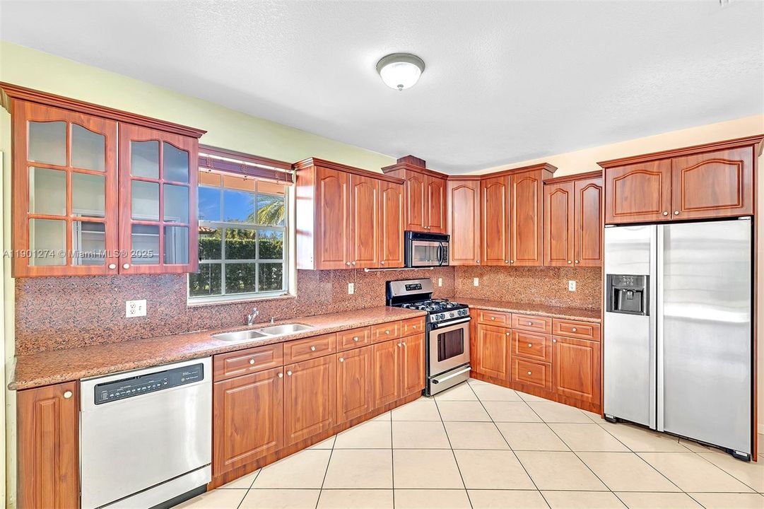 Ample kitchen, with granite counters, gas range, and large pantry.