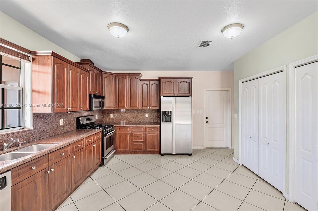Ample kitchen, with granite counters, gas range, and large pantry.