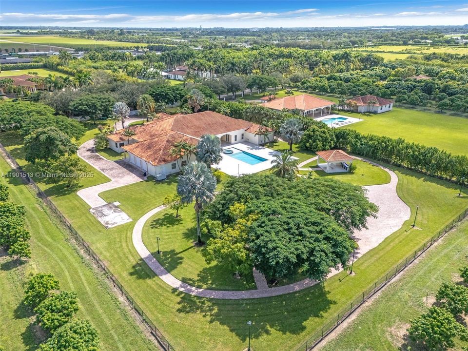 REAR VIEW OF THE ESTATE - POOL / SPA, POOL BATH W/ SUMMER KITCHEN, WELL LIT, LUSH LANDSCING W/ LARGE OPEN AREA READY FOR DINING AFRESCO OR BRING IN THE TENT. COSSED FENCE FROM THE GROVE.ENJOY AN EVENING STROLL THRU THE GROUNDS.