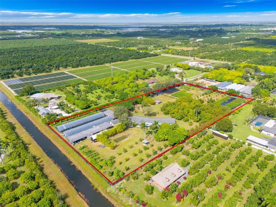 BACK OF THE PROPERTY W/ VIEW OF SHADE HOUSES, WATER FEATURE, GROVE AREA.
