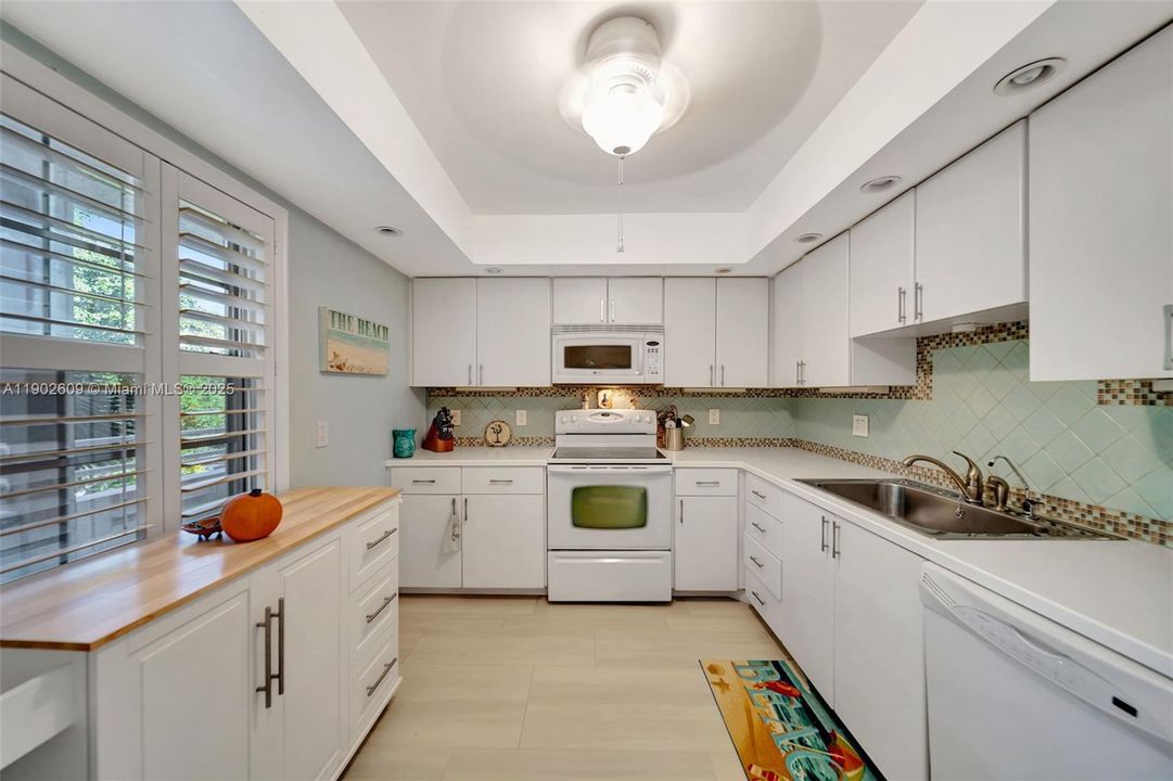 A full U-shaped layout with wraparound counters, undermount lighting, and classic white appliances makes meal prep effortless.