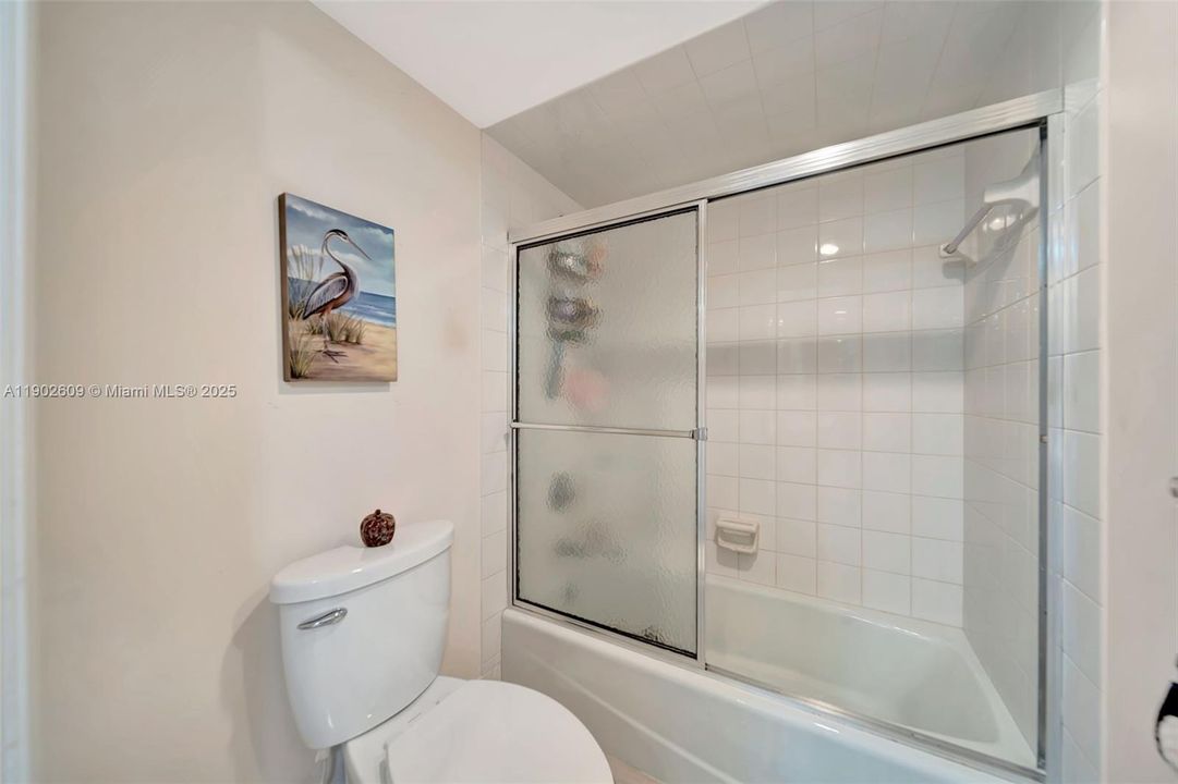 Bright and well-kept full bath featuring a tub/shower combo with sliding glass doors, clean tile surround, and neutral finishes