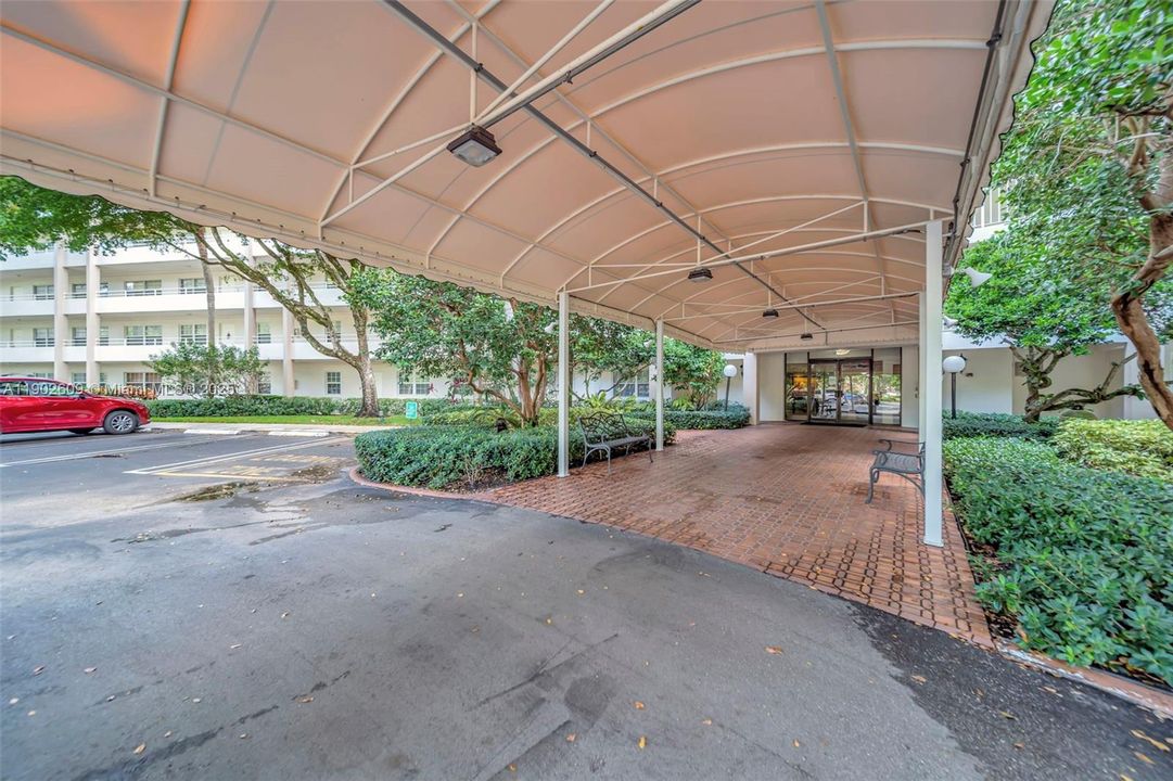 Covered, convenient, and welcoming — the porte cochère entry offers shaded drop-off and easy access to the lobby, surrounded by mature landscaping and a well-kept building exterior.