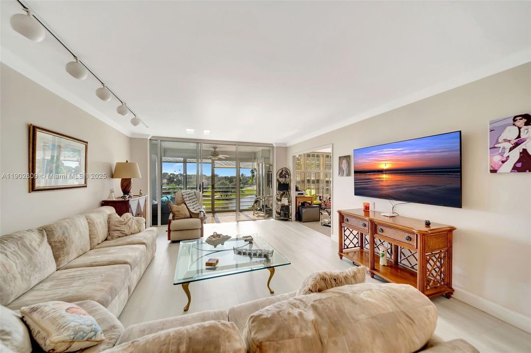 Spacious great room with multiple seating zones and direct access to the enclosed patio—perfect for relaxing while overlooking the greens and water.