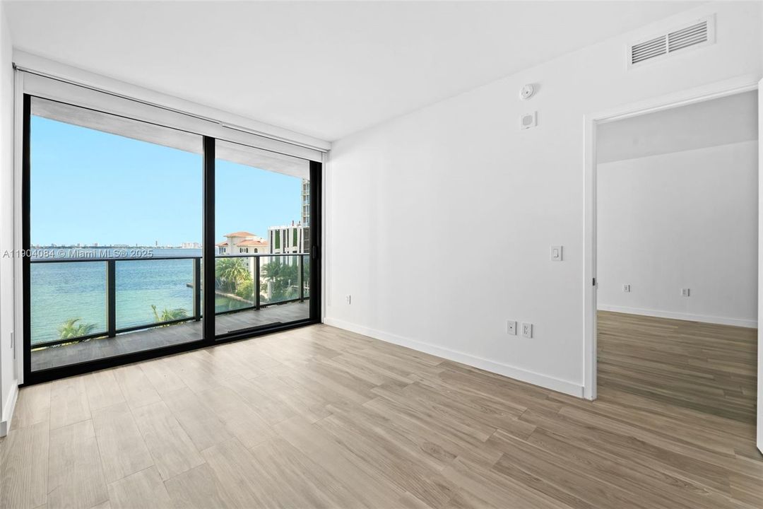 Spacious primary bedroom with floor-to-ceiling windows and direct Biscayne Bay views.