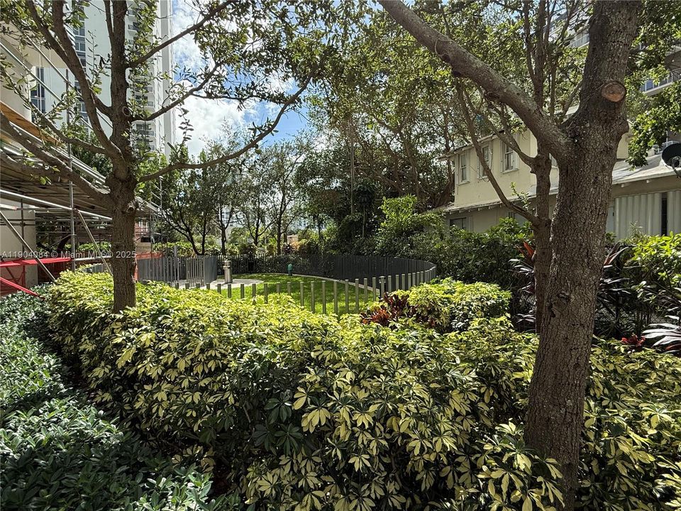 Private pet park with walking paths, palm trees, and serene bay views for residents to enjoy.