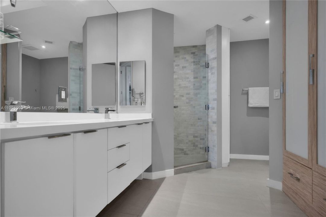 Luxurious primary bath: iridescent mosaic shower, dual vanity & custom finishes.