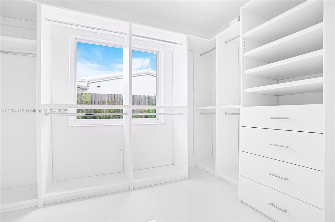 Extensive Cabinetry in Primary Bedroom Closet with Daylight