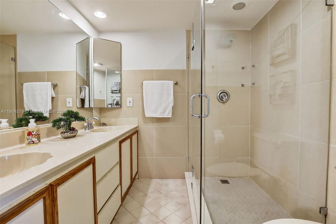 En-suite bathroom with clean, bright finishes, large wall tile and new shower tile and glass frameless shower door and functional design.