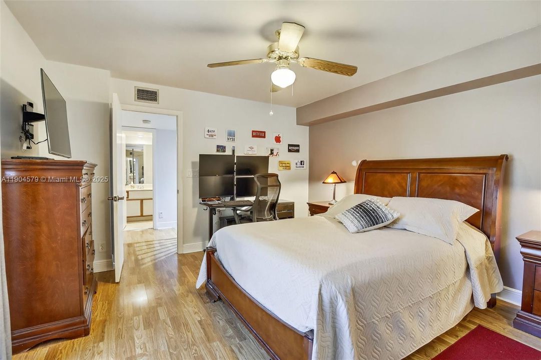 Large primary bedroom with laminate flooring, private balcony, walk in closet and serene garden views.