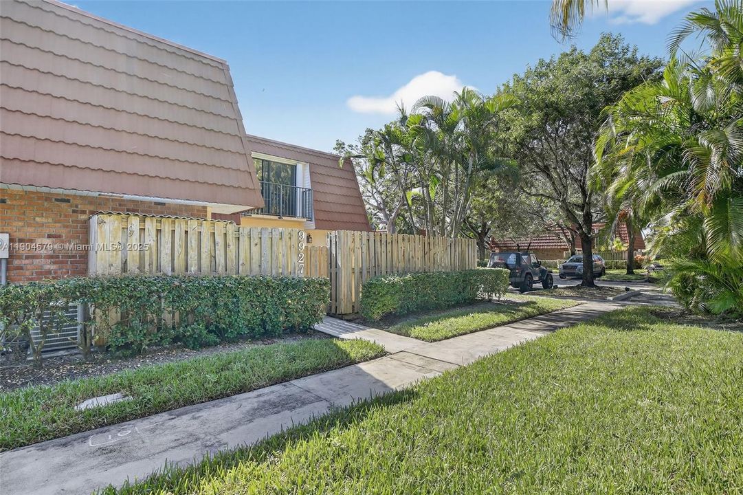 Lush, tree-lined front yard offering great curb appeal and a peaceful neighborhood setting. Sidewalk in front of the building, takes you to two assigned parking spaces
