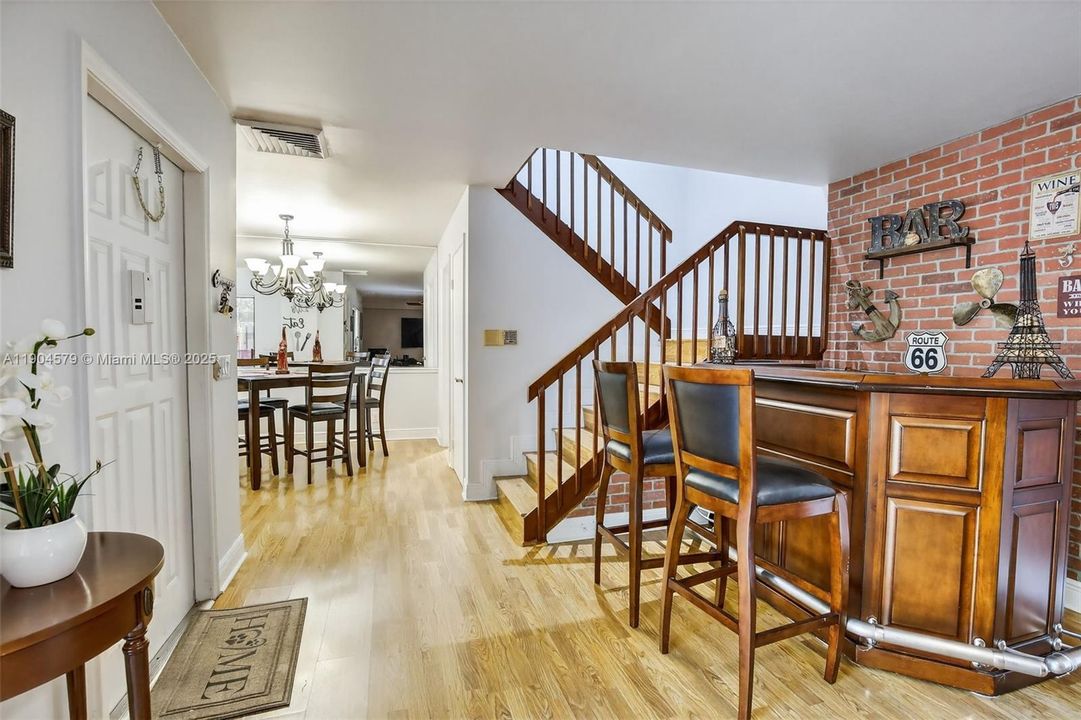 Bright open-concept living area filled with natural light and stylish laminate flooring, neutral paint and flat ceilings.
