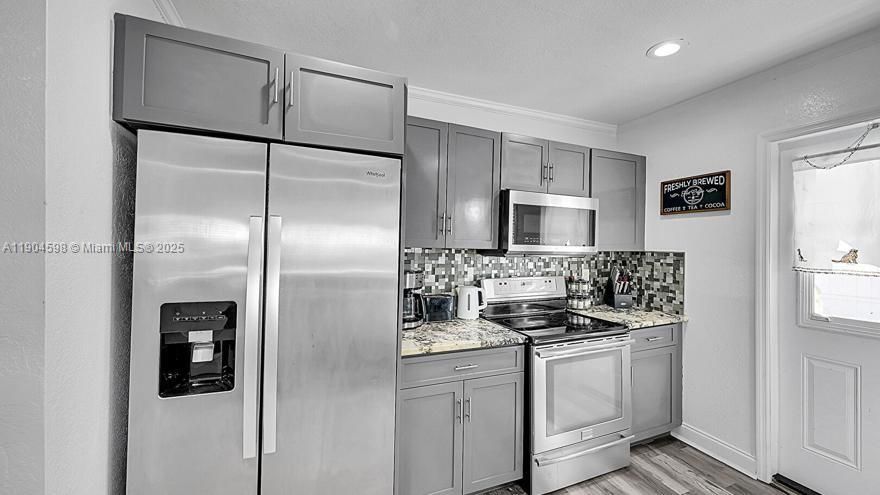 Arched Walkways, Baseboards Wall, Crown Molding, Drywall, Gray Cabinets, Kitchen Peninsula, Natural Light, Opens To Living Area, Pass Through Window, Recessed Lighting, Shaker Cabinets, Stone Countertops, Textured Ceiling, Textured Wall, U Shaped Kitchen, Vent, Wood Finish Floor, Arched Walkways, Drywall, Shaker Cabinets, Textured Ceiling, Vent