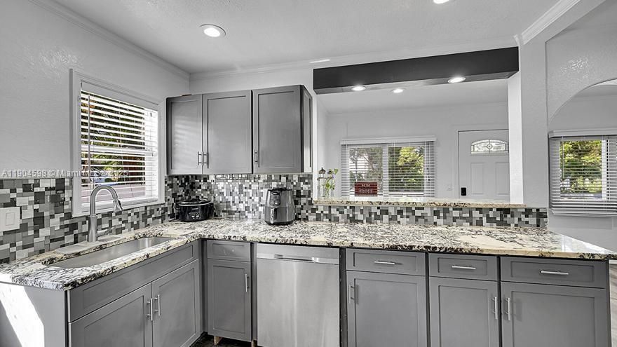 Arched Walkways, Baseboards Wall, Crown Molding, Drywall, Gray Cabinets, Kitchen Peninsula, Natural Light, Opens To Living Area, Pass Through Window, Recessed Lighting, Shaker Cabinets, Stone Countertops, Textured Ceiling, Textured Wall, U Shaped Kitchen, Vent, Wood Finish Floor, Arched Walkways, Drywall, Shaker Cabinets, Textured Ceiling, Vent