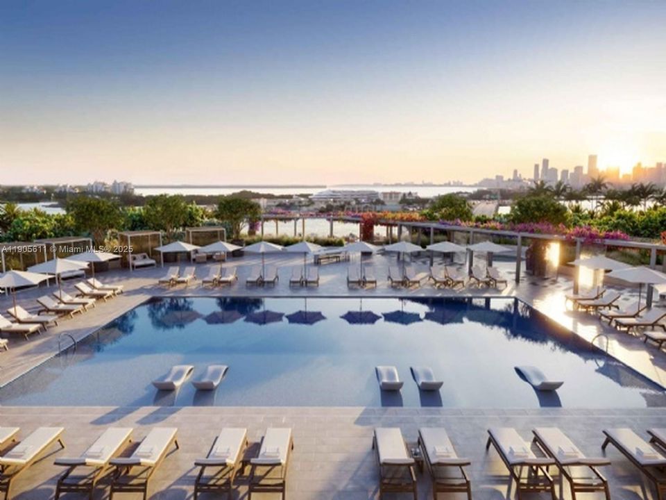 Resort-style pool deck at Five Park Miami Beach overlooking Biscayne Bay and the downtown skyline at sunset.